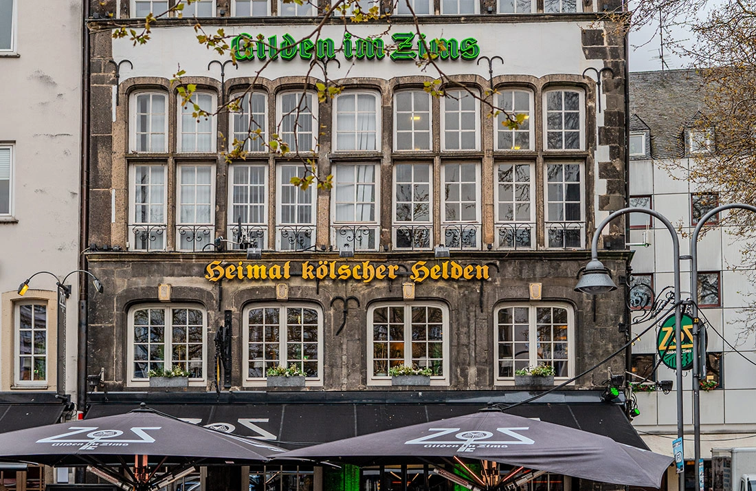 Ein mehrstöckiges Gebäude mit historischer Fassade und zahlreichen Fenstern steht im Vordergrund.