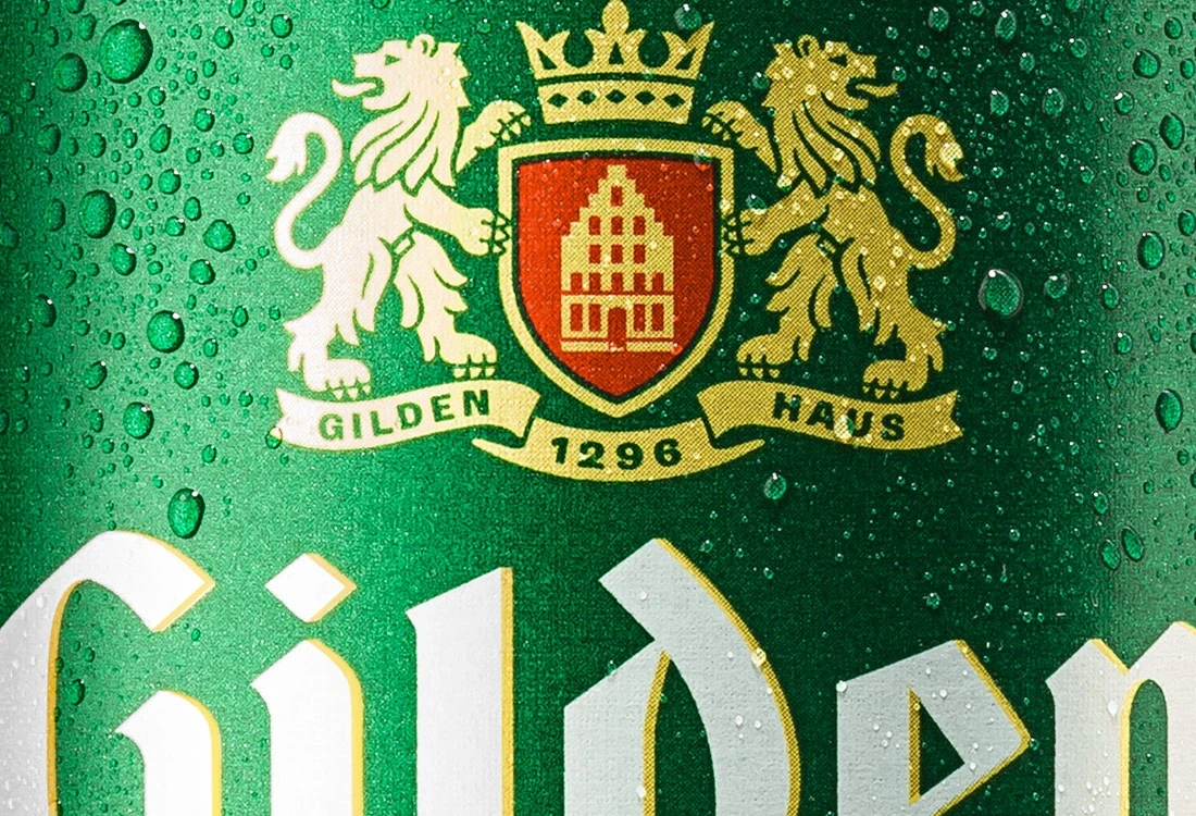 Nahaufnahme eines grünen Emblems mit zwei Löwen und einer Krone, umrandet von Wassertröpfchen.